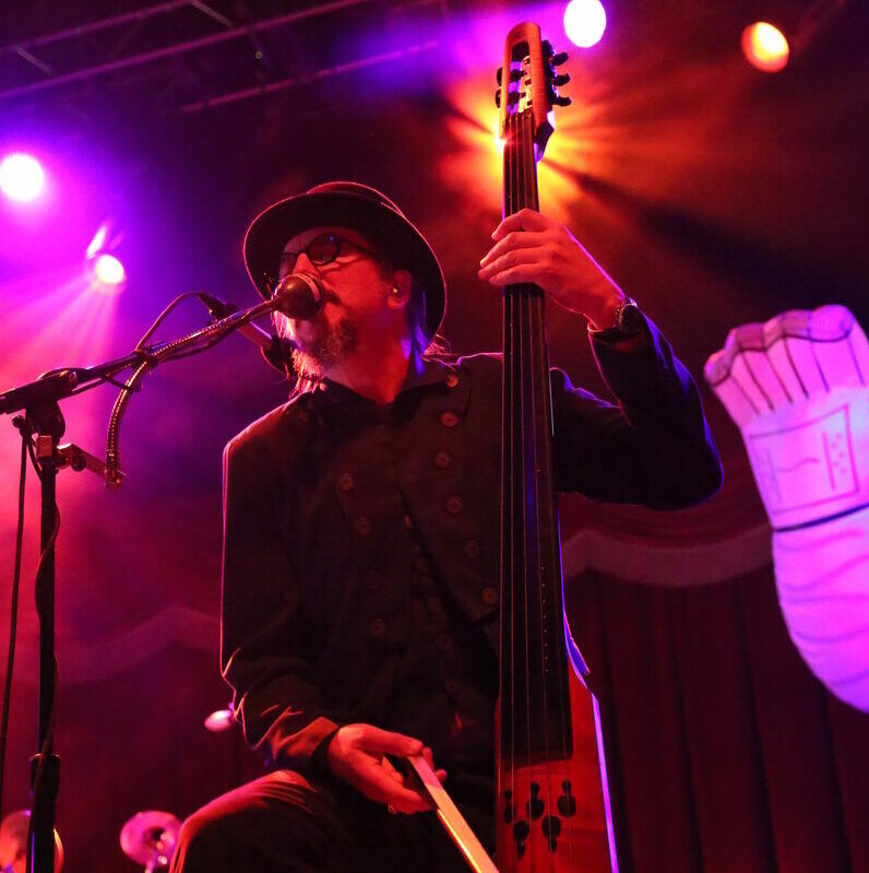 Photograph of NS Design Artist Les Claypool playing his CR5M Electric Upright Bass with Primus. Photo by Josh Keppel